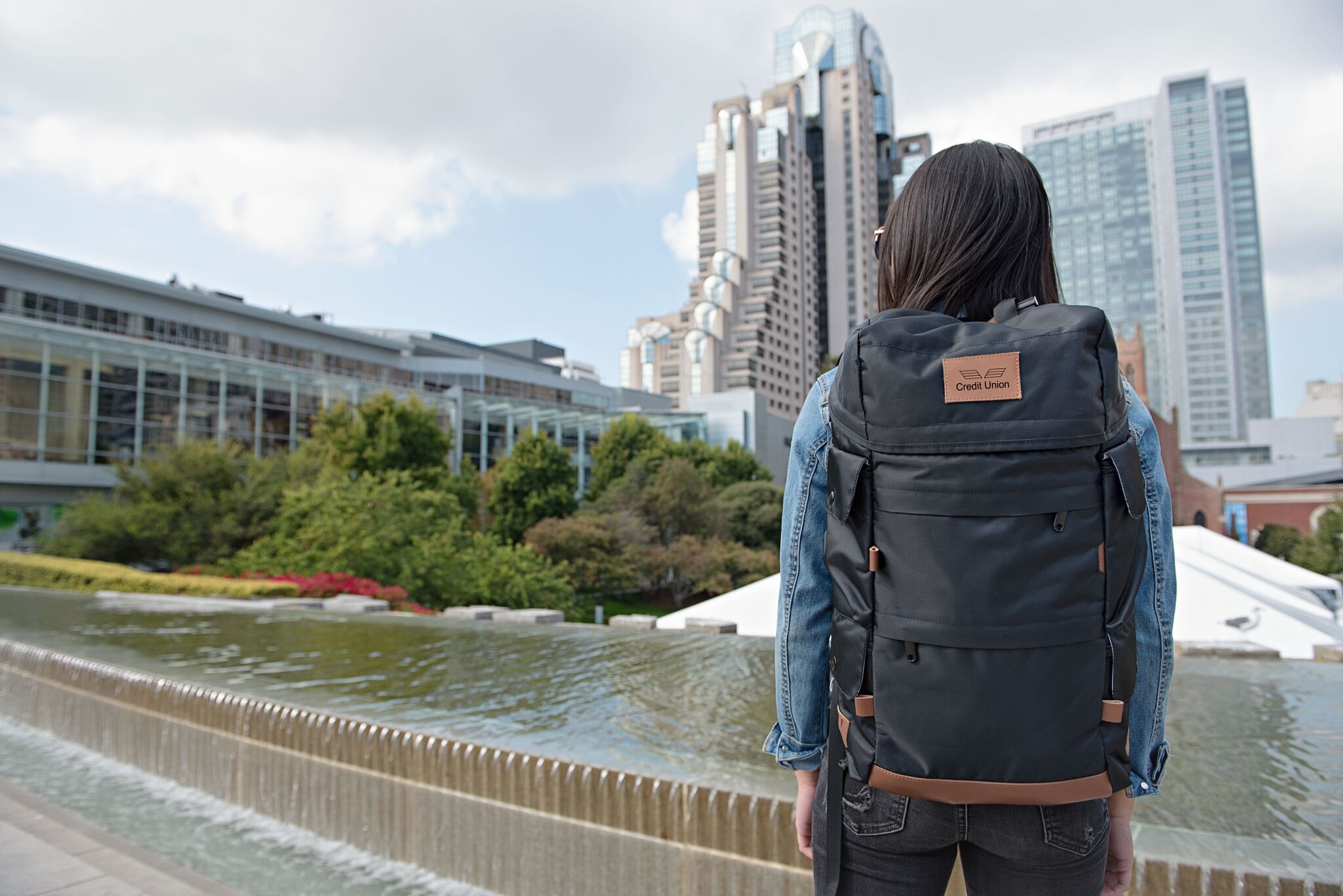 A woman overlooking a city, wearing branded backpack.